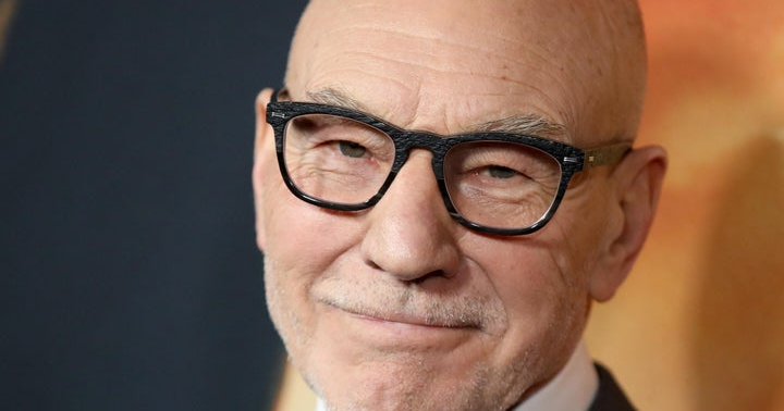 Close-up portrait of Patrick Stewart wearing black-framed glasses.