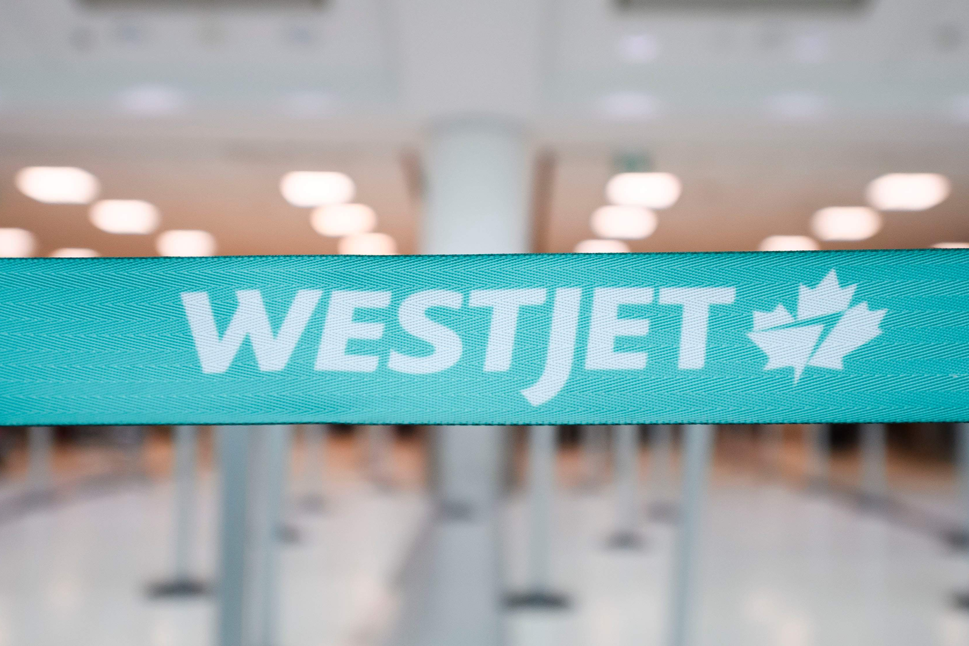 A turquoise WestJet-branded queue barrier in an airport check-in area.
