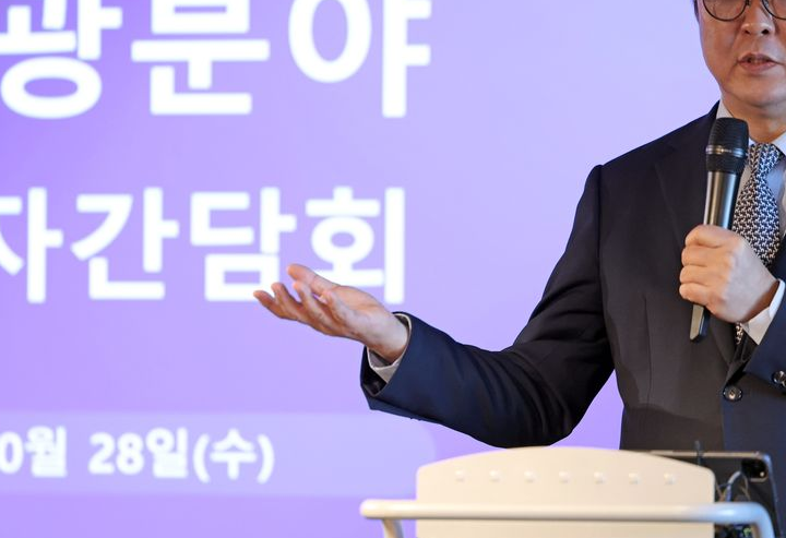 Culture, Sports and Tourism Minister Choi Hwi-young speaks into a microphone at a tourism press briefing. The crop cuts off the top of his head and part of his body.