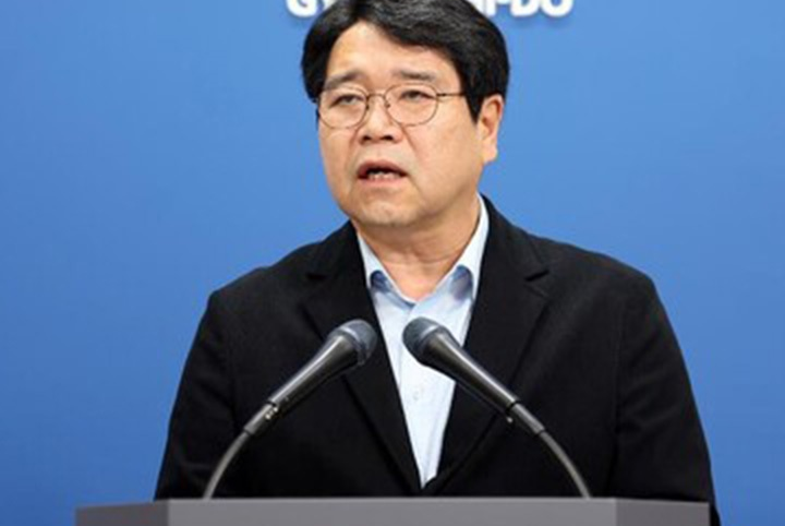 Yoon Tae-wan, Gyeonggi Province’s transport bureau director, speaks into two microphones at a podium against a blue backdrop.