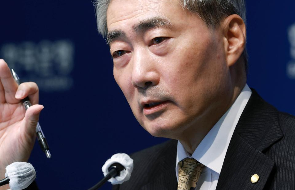 Bank of Korea Governor Shin Hyun-song speaks into microphones with one hand raised holding a pen.