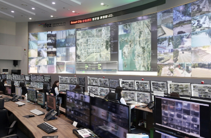 People working in an IFEZ monitoring room equipped with a large wall display and multiple monitoring screens