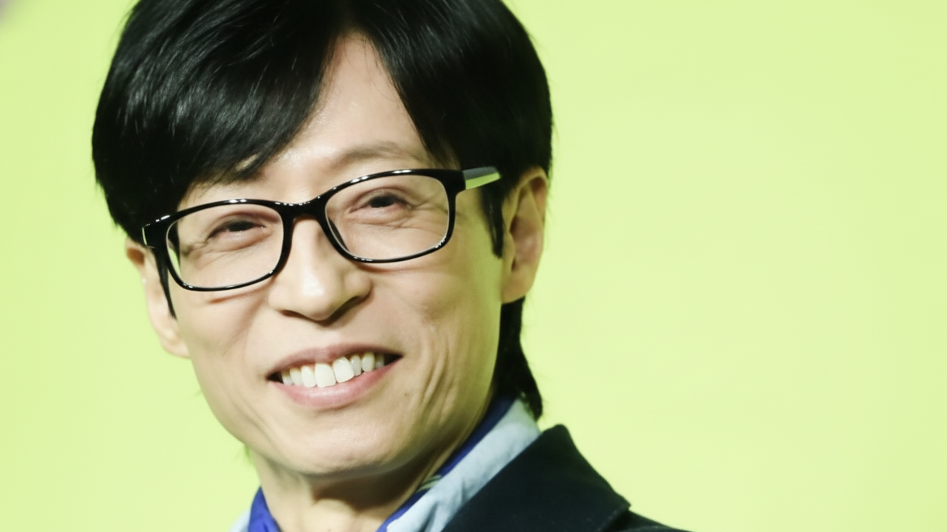 안경을 쓰고 미소 짓는 방송인 유재석