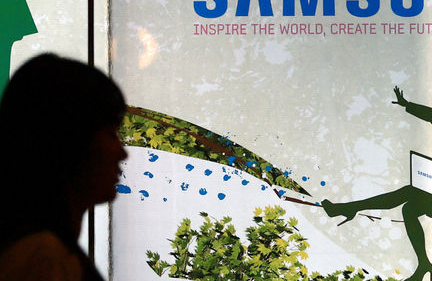 Side view of a person walking past a glass wall displaying a Samsung advertisement