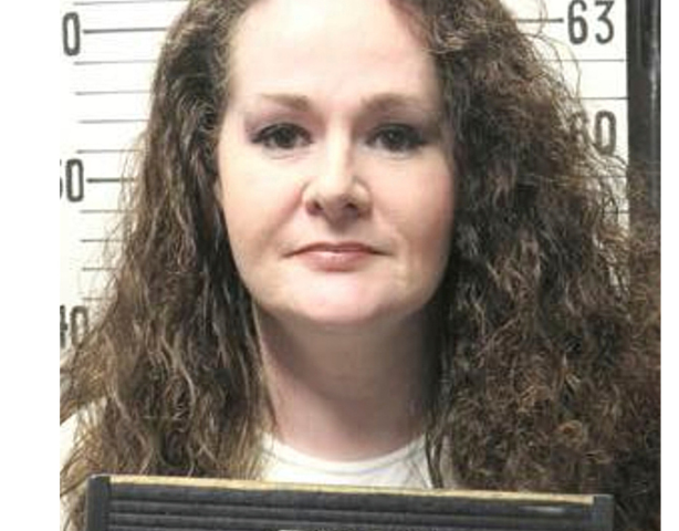 Christa Pike in a correctional identification photograph, with a height chart behind her.